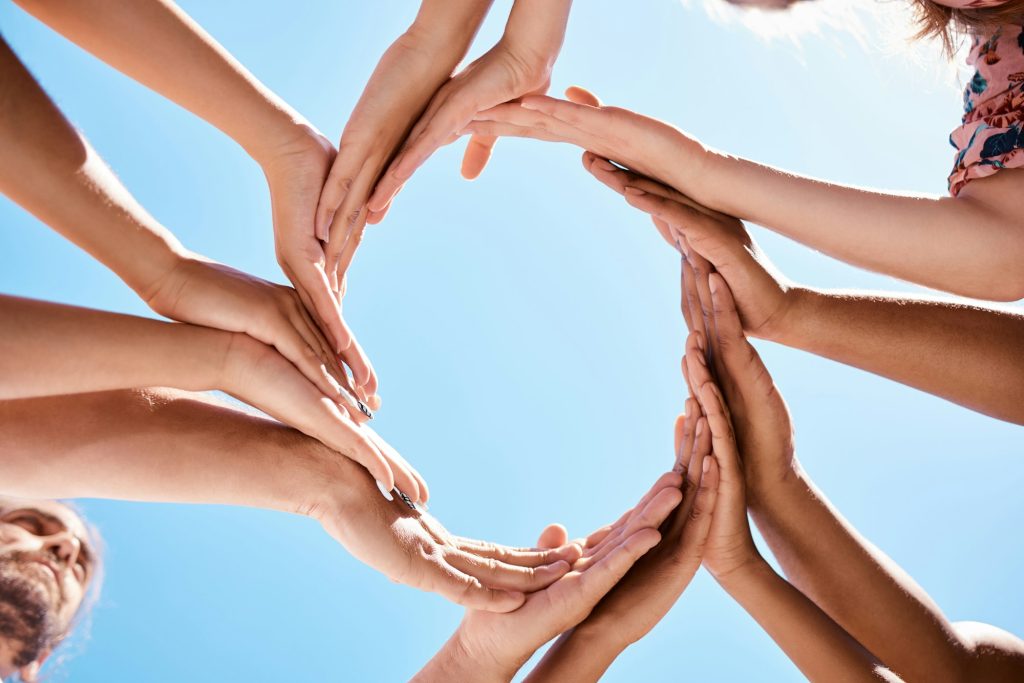 Hands, circle and community support hand sign of people and friends outdoor with a blue sky. Happy,