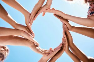 Hands, circle and community support hand sign of people and friends outdoor with a blue sky. Happy,