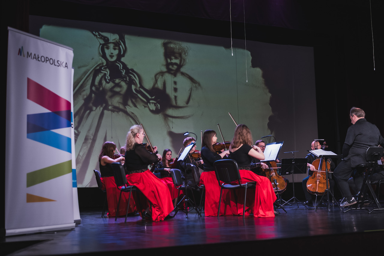 orkiestra smyczkowa a w tle animacja piaskiem